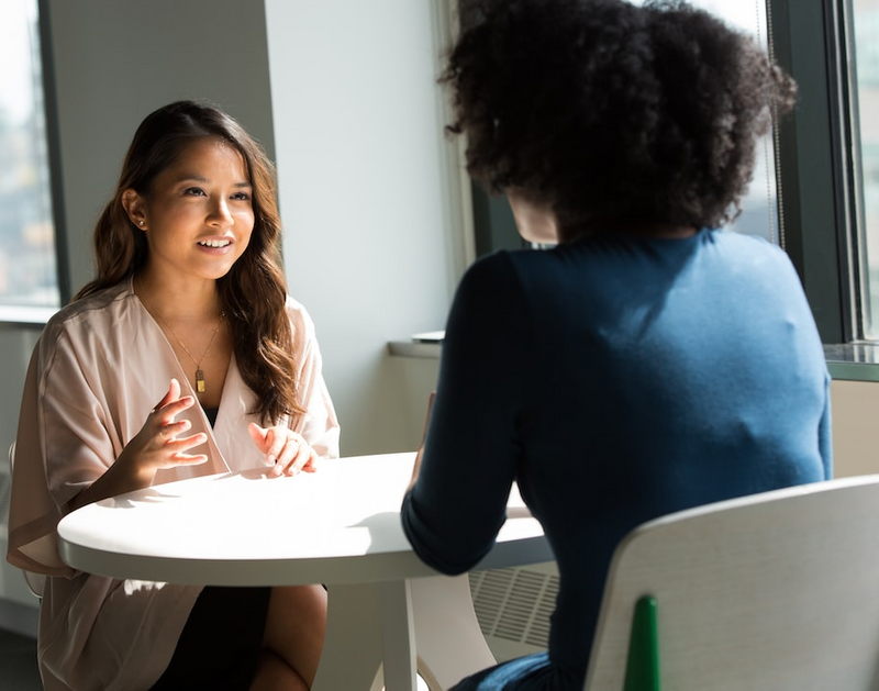 Two women sitting at a table engaged in a conversation.