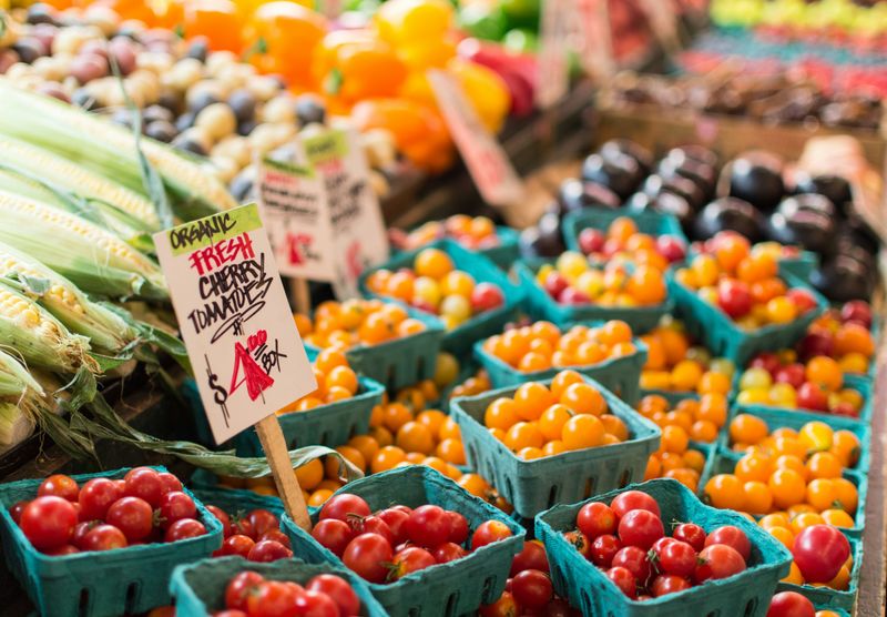 Fresh cherry tomatoes, corn, and other produce at a farmer's market.