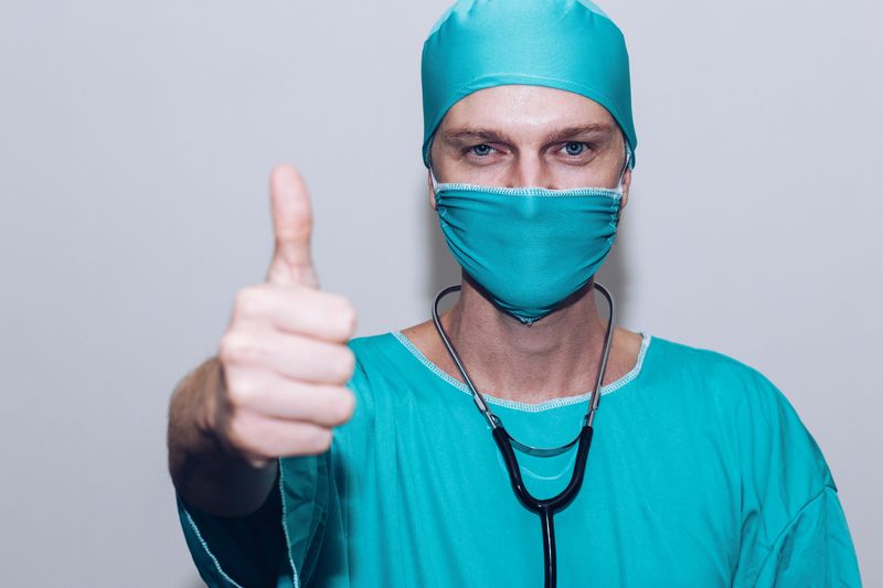 A doctor in full scrubs giving a thumbs up