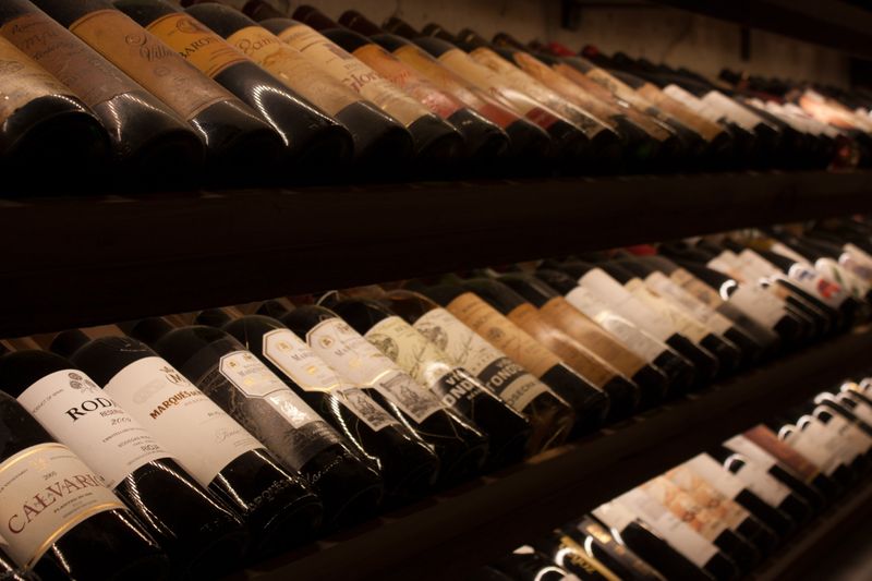 Many different types of wine laying on angled shelves