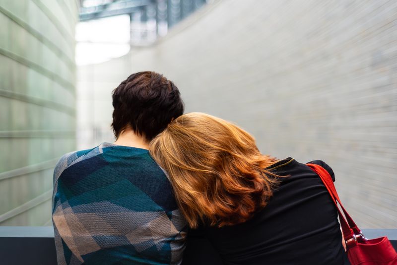 One person resting their head on the shoulder of another person.