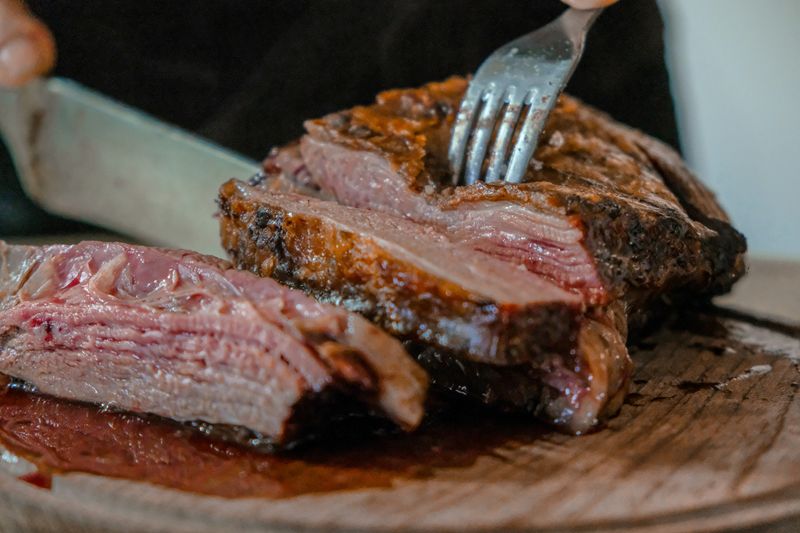 A person slicing meat on a cutting board.
