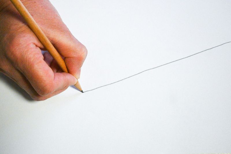 A hand using a pencil to draw a line. 