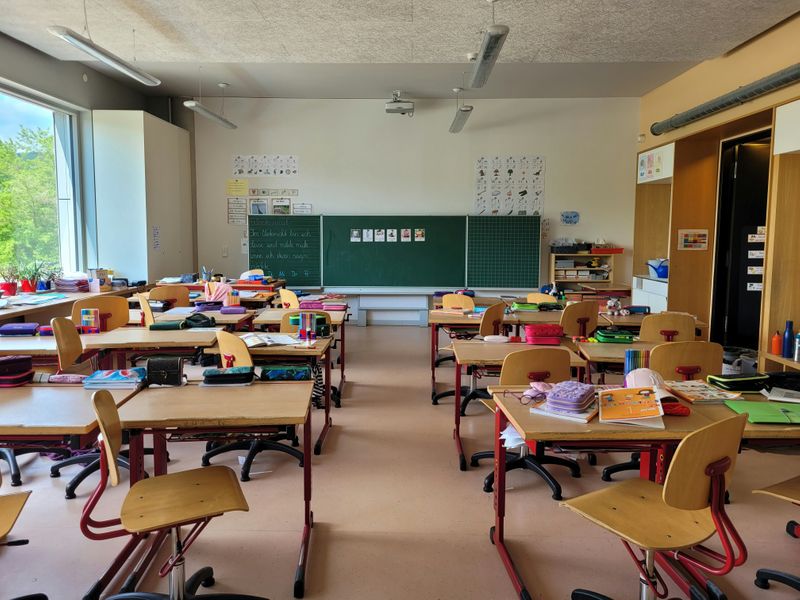 A classroom with desks, chairs and a blackboard.