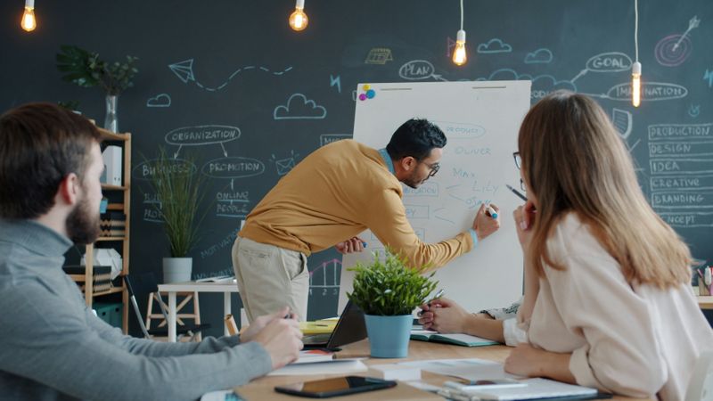 Man and woman paying attention to man writing on a whiteboard