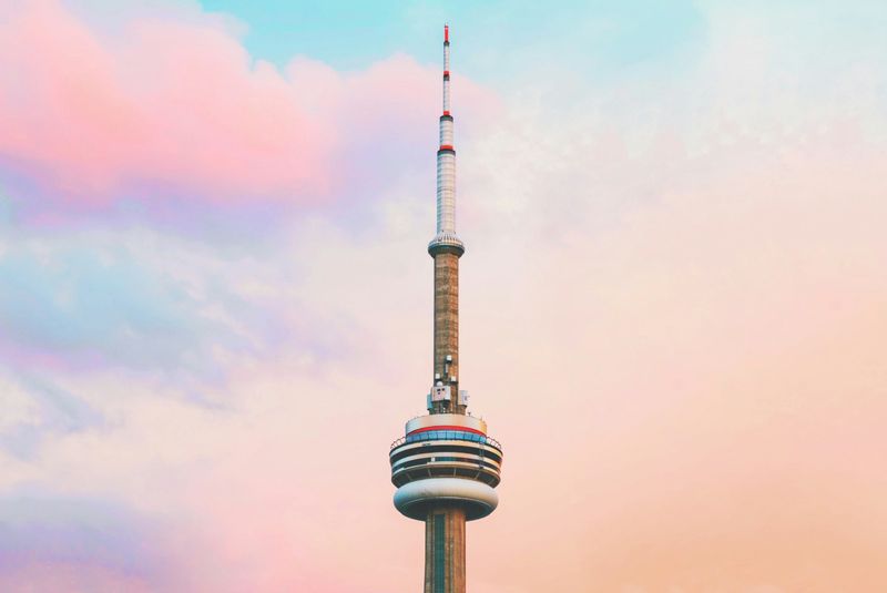 The CN Tower in front of a partially cloudy sky.
