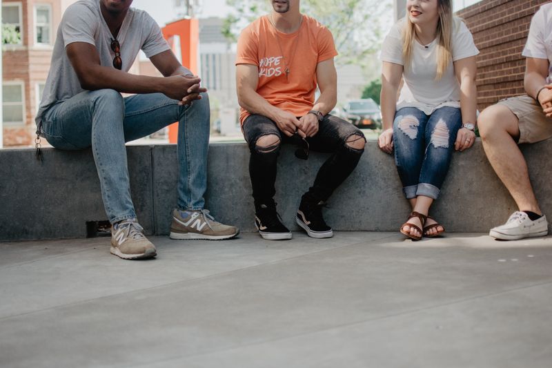 A group of four people sitting together and talking on a concrete ledge