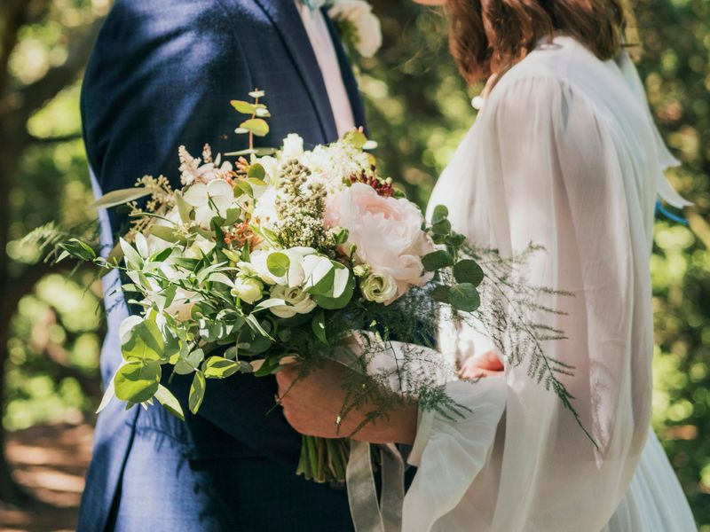 A couple holding a boquet of flowers.