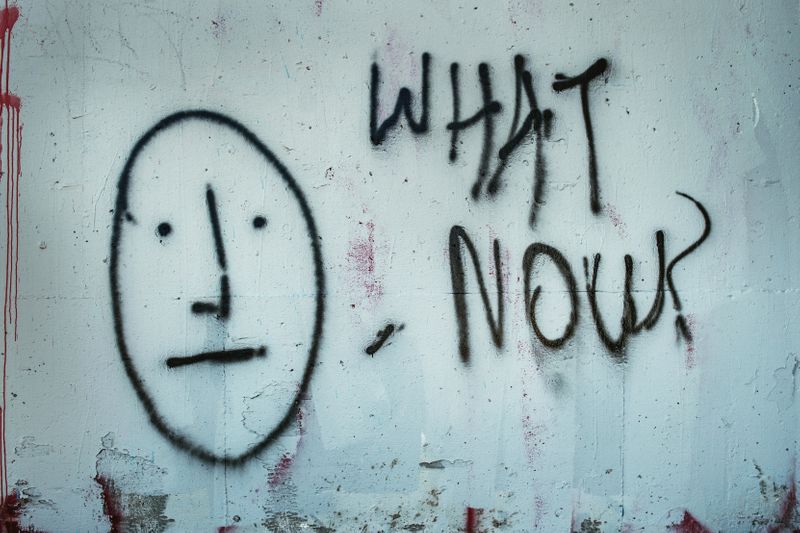 Graffiti on a wall that reads, 'What now?'