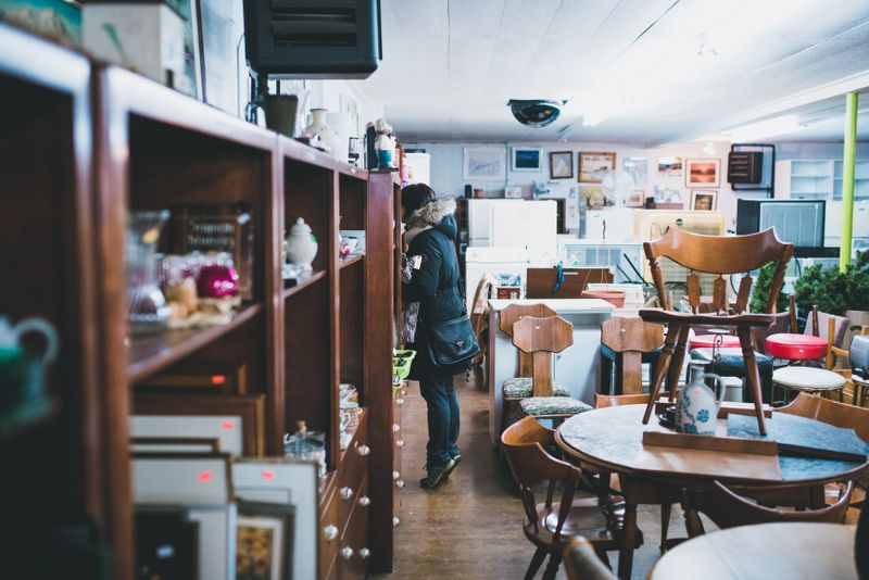 A second-hand furniture store. A customer looks at items on a shelf.