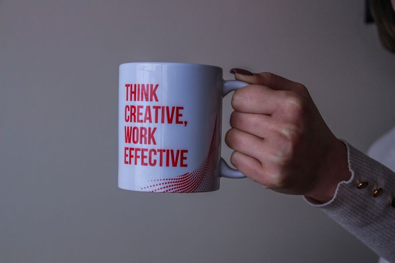 Person, holding a mug that reads 'Think creative, work effective.'