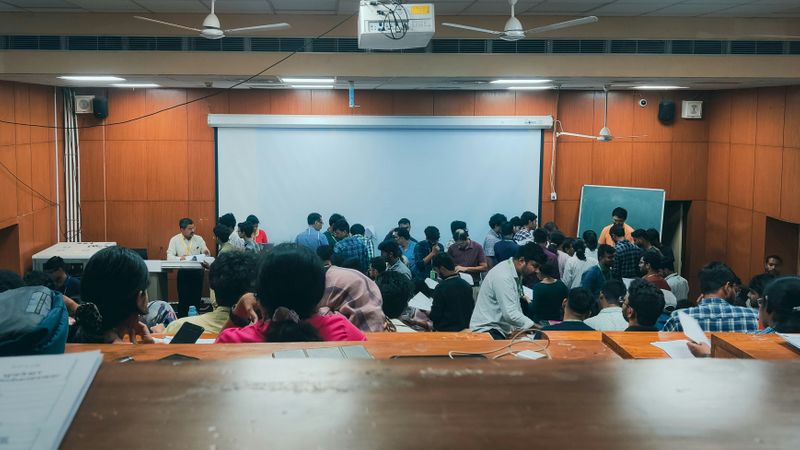 A group of students mingles in a lecture room.