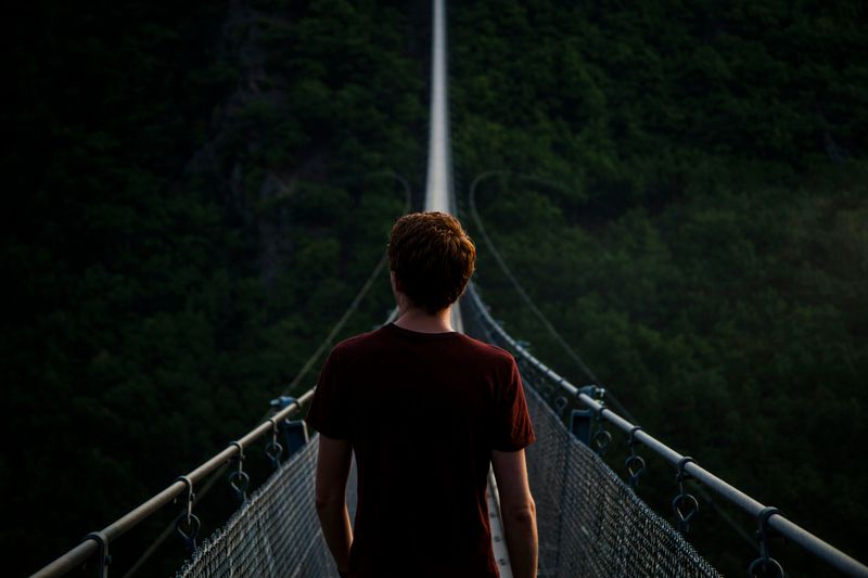 A person focusing on the goal of crossing a suspension bridge.