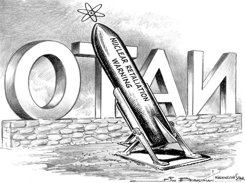 A political cartoon. A missile stands behind a NATO sign. The text on the missile says, "nuclear retaliation warning".