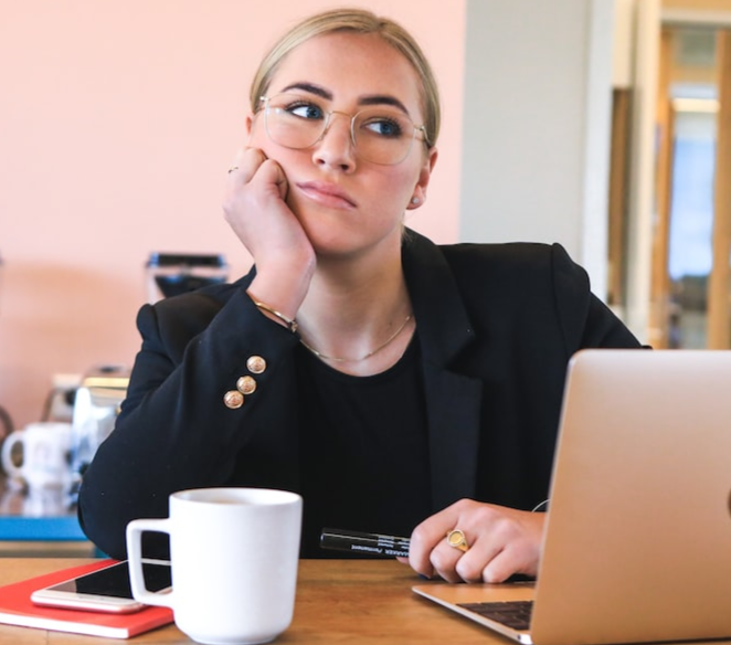 A woman in front of a laptop thinking deeply