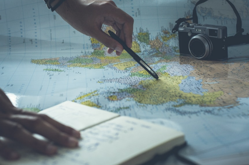 A person scanning a travel map with a pen.