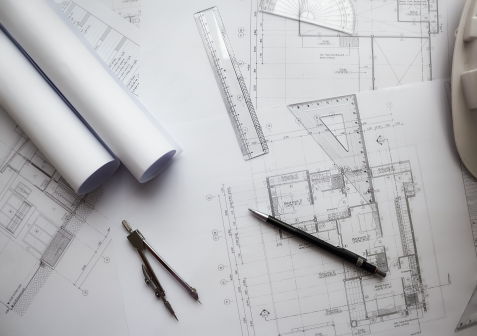 An architectural drawing with rulers, a compass, and other drafting tools.