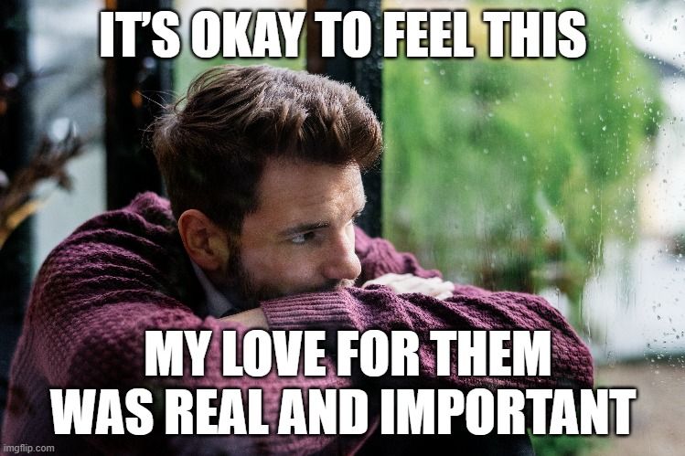 A sad man sits by a rainy window, thinking, “It’s okay to feel this. My love for them was real and important.”