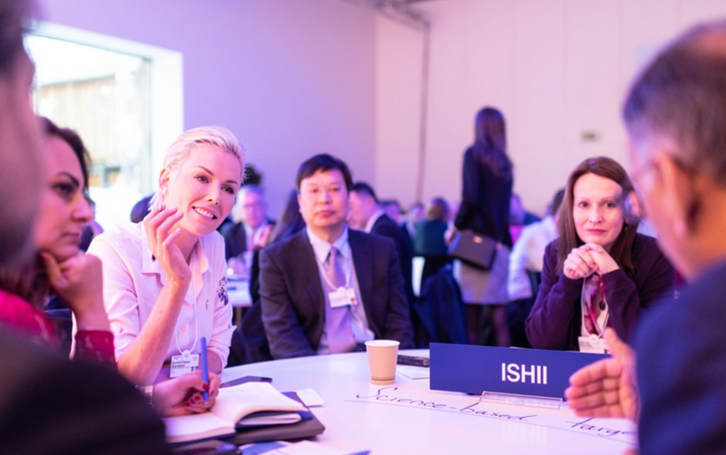 A group of colleagues sitting at a table, taking notes and having a collaborative conversation.