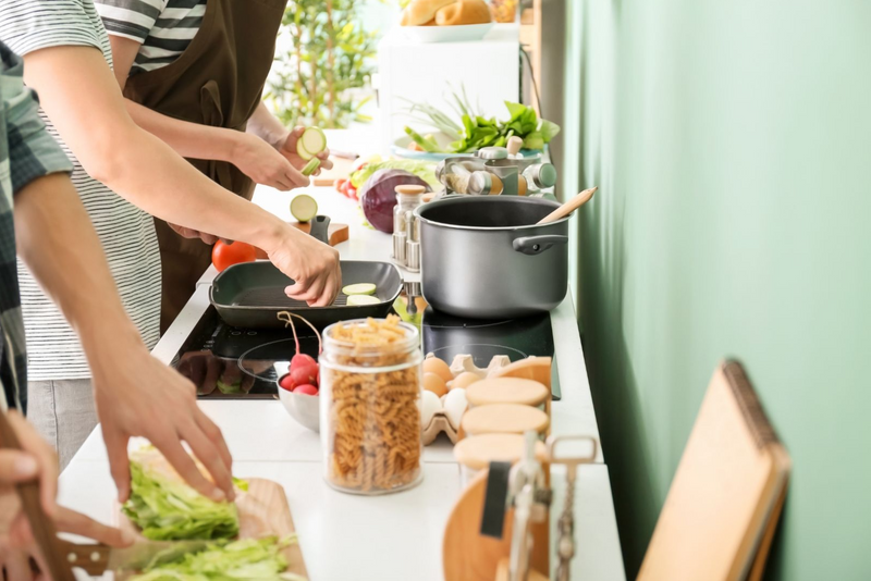 An image of three people preparing a healthy meal together. 