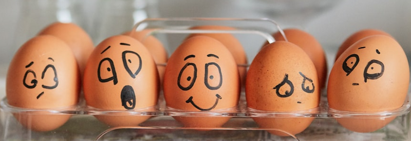 Varying emotions sketched with a marker on five brown eggs. 