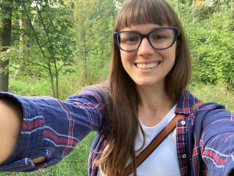 Adult smiling while taking a selfie outdoors