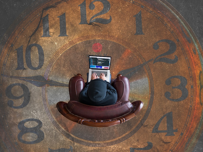 Peson sitting in front of computer screen in the middle of a clock.