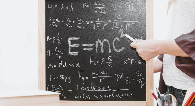A black board is filled with complicated equations using a lot of special characters.