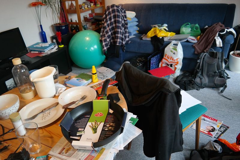 Extremely messy living room with plates and clothes strewn about