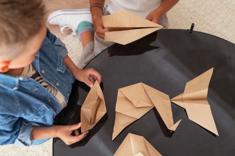 Two students create paper airplanes and boats.