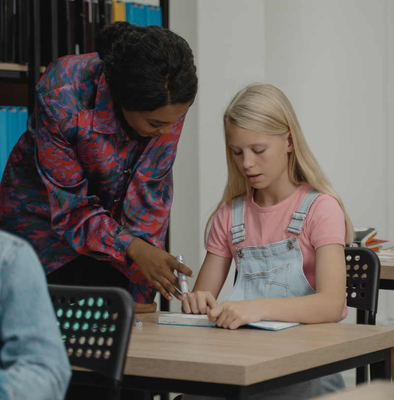 Photo of teacher helping student sitting at desk