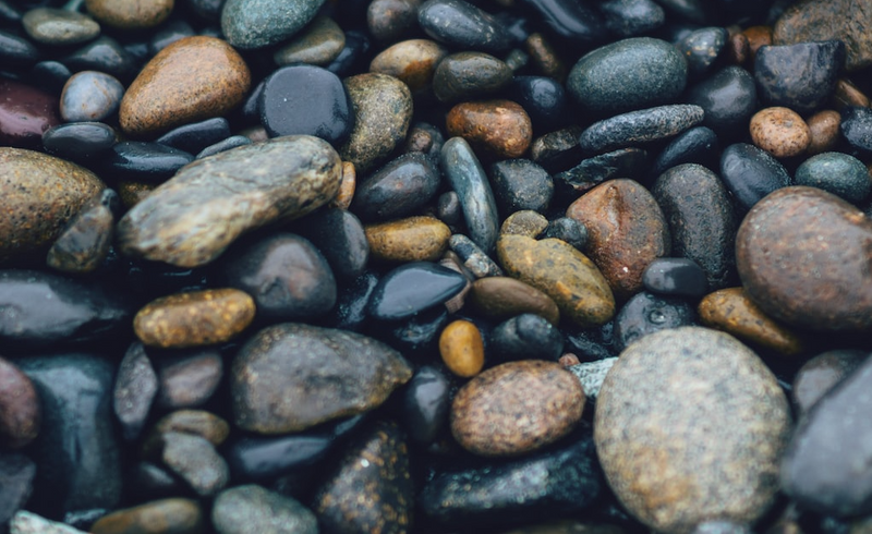 Image with different types of wet rocks, stones and pebbles in neutral earth-tone colors