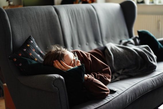 Young girl laying on couch with eyes slightly open