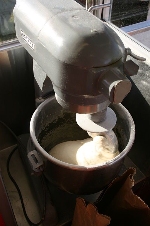 vintage stand mixer with dough in the bowl and wrapped around the spiral attachment. 