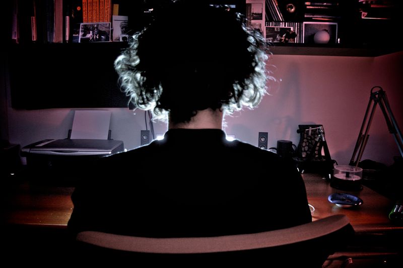 A person looks at a computer screen in a dark room.