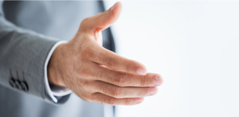 A man wearing a suit extending his hands for a handshake