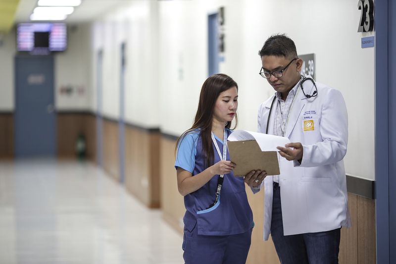 A medical assistant and a doctor reviewing a patient chart.