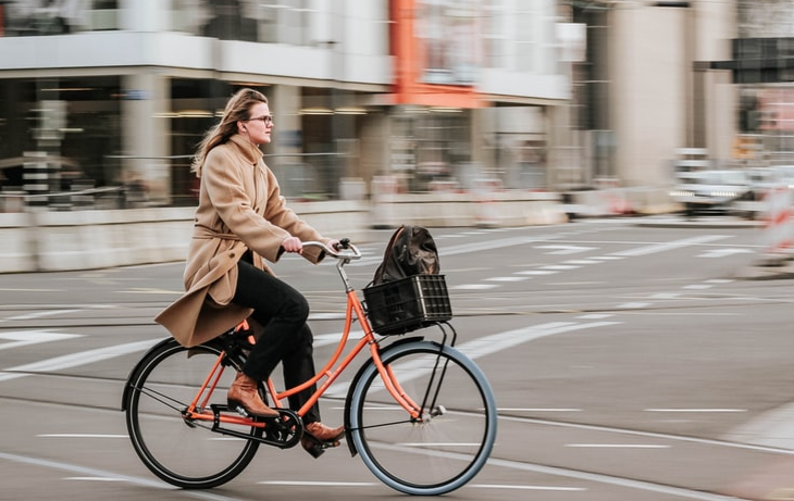 A woman riding a cruiser bike across a city street