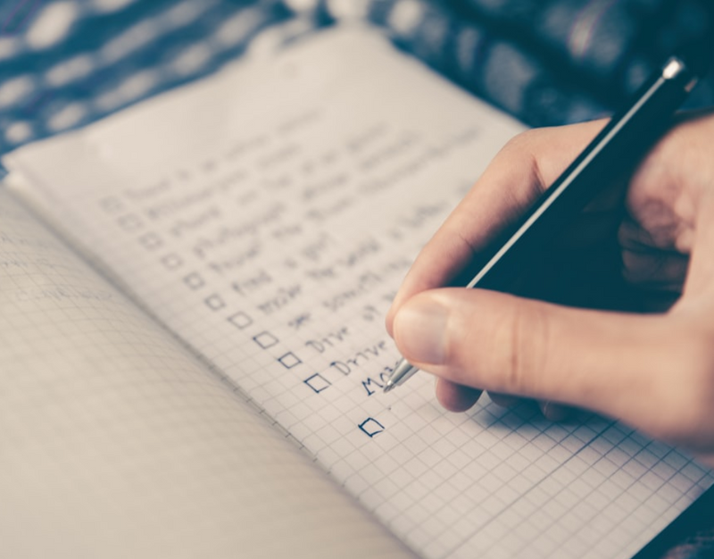 A person ticking off a checklist in a notebook.