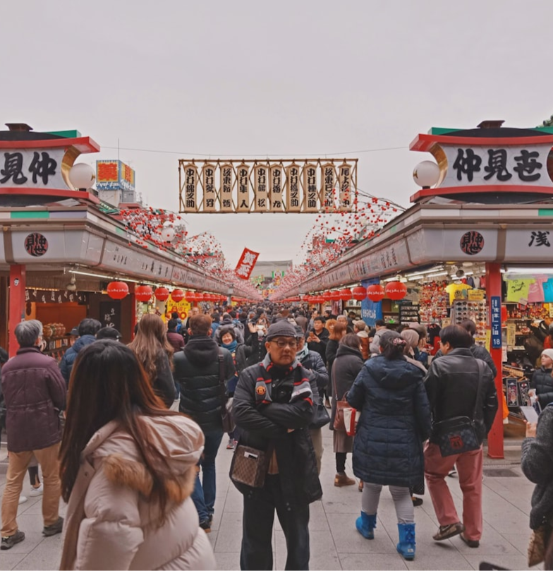 A man is standing in the middle of a crowded market, looking lost and confused.