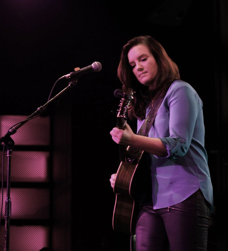 Brandy Clark on stage playing guitar in front of microphone