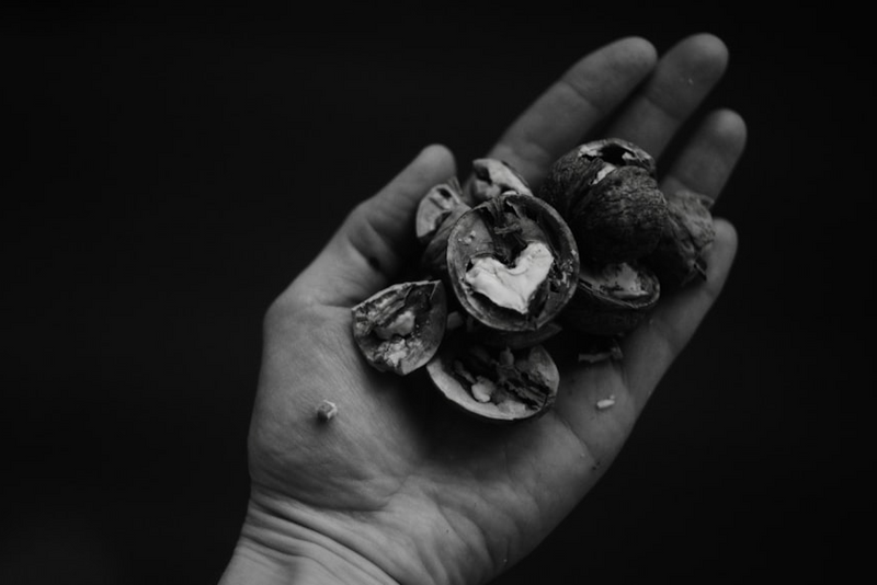 A hand holding walnut shells with a heart inside, representing something positive on the inside.