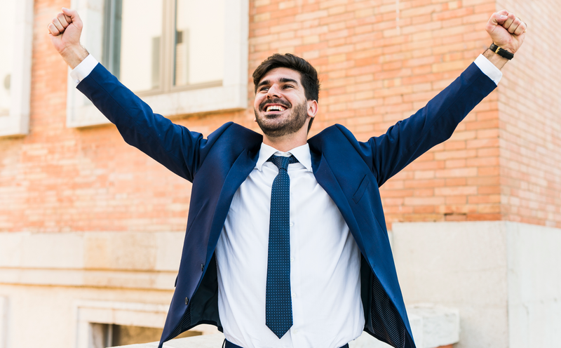 A young Certified Public Accountant in a suit celebrates.