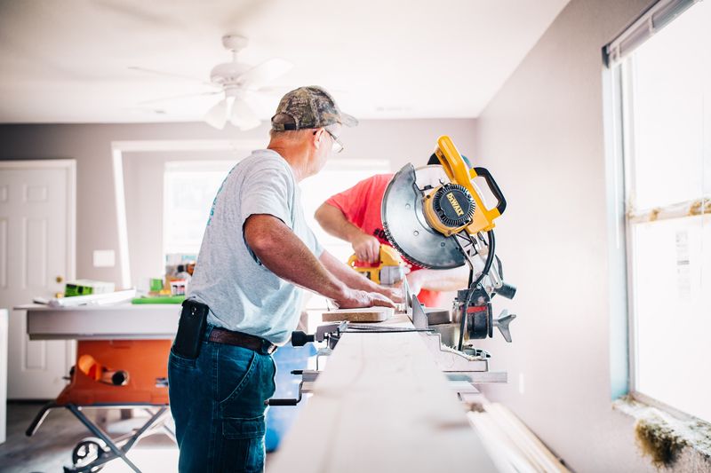 Two men cutting a blank of wood with an electrical saw