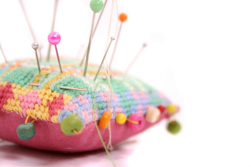 Image of colorful sewing pins stuck in a pincushion.