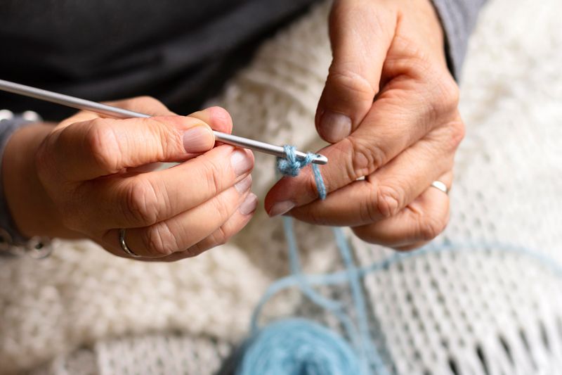 A close up of a person's hands making knots on a crochet hook.