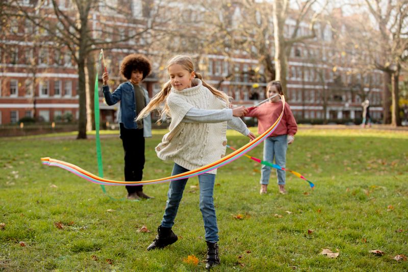 A group of students playing with ribbons in a schoolyard.