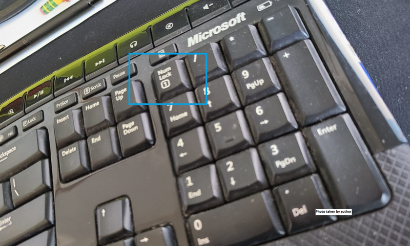 A black keyboard is on a desk and the key for 