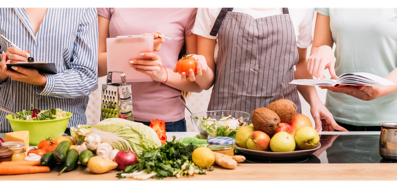 An image of four people getting ready to cook a healthy meal with fresh vegetables. 