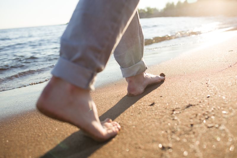 A person walking barefoot on a seashore.